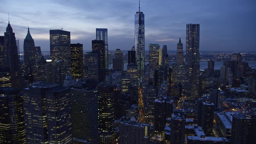 A metropolitan city with huge buildings at dusk with building lights on