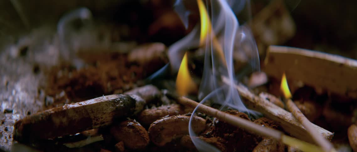 Some matchsticks burning next to cigarette butts