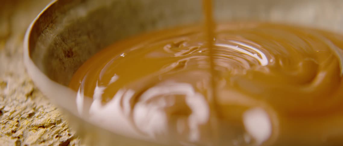 Poured sauce fills bowl on textured surface