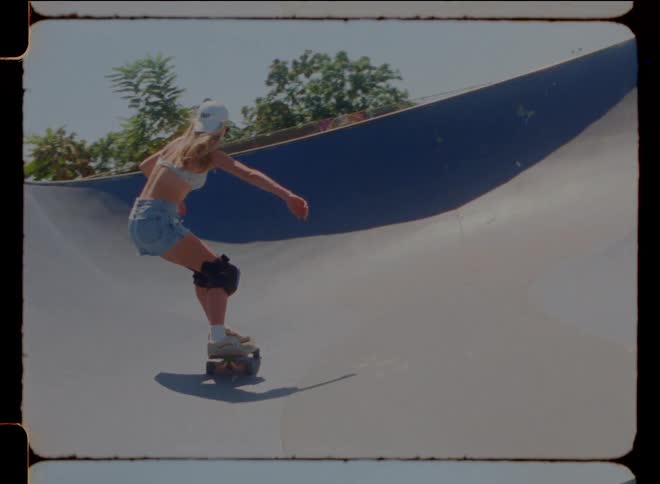 A tall woman skateboards around a large pool with sloped sides