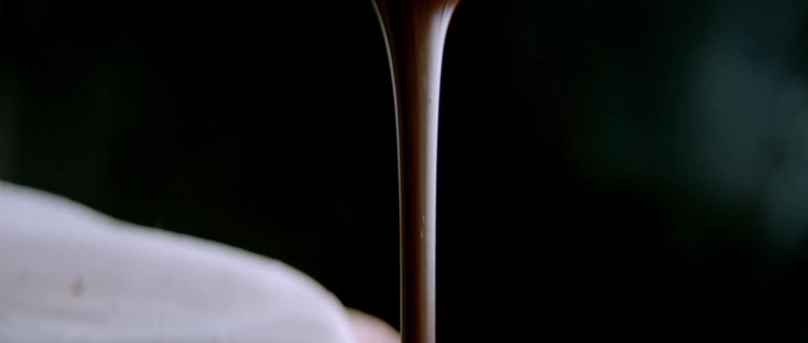 Hands hold a steel bowl and a viscous batter is stretched from the bowl