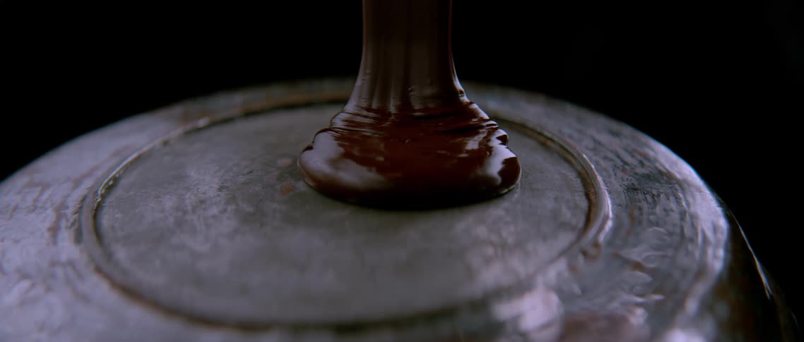 Close up of thick chocolate pouring over a plate