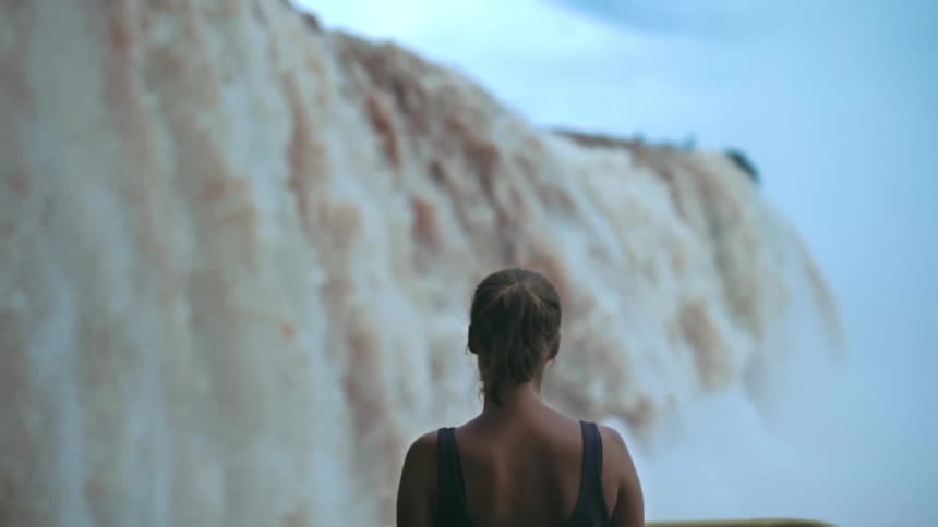 Woman facing both towards and away from a waterfall in free fall