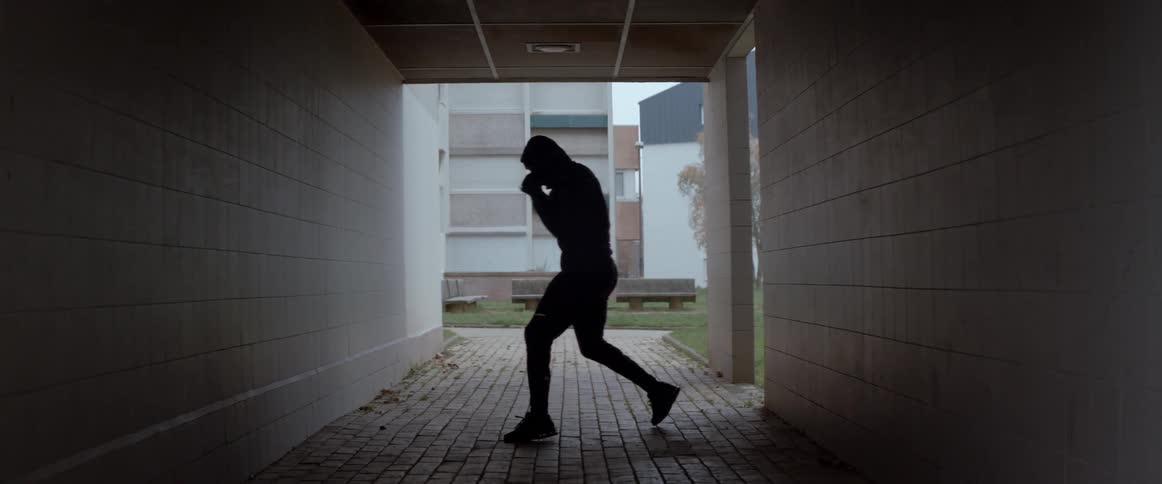Silhouette of a man shadowboxing near a building