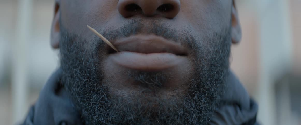 A toothpick in a mans mouth