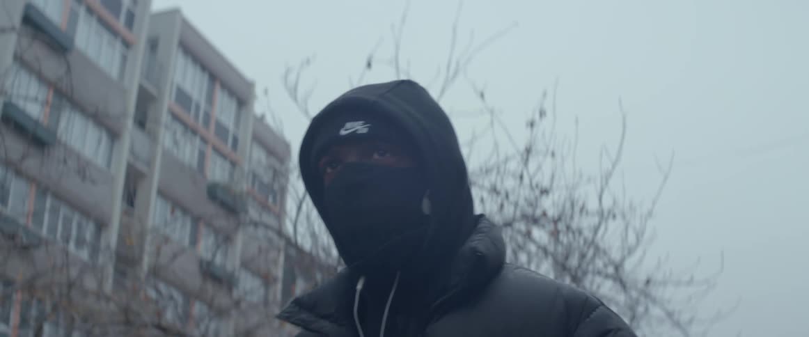 A person wearing mask and a hoodie walking in the street