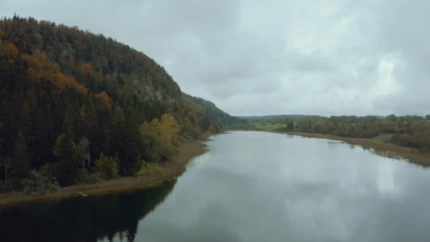 Panorama of a serene river with forests around it under a cloudy sky