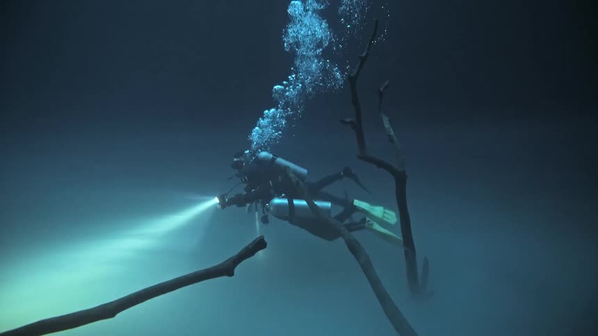 Divers underwater swimming with a powerful flashlight