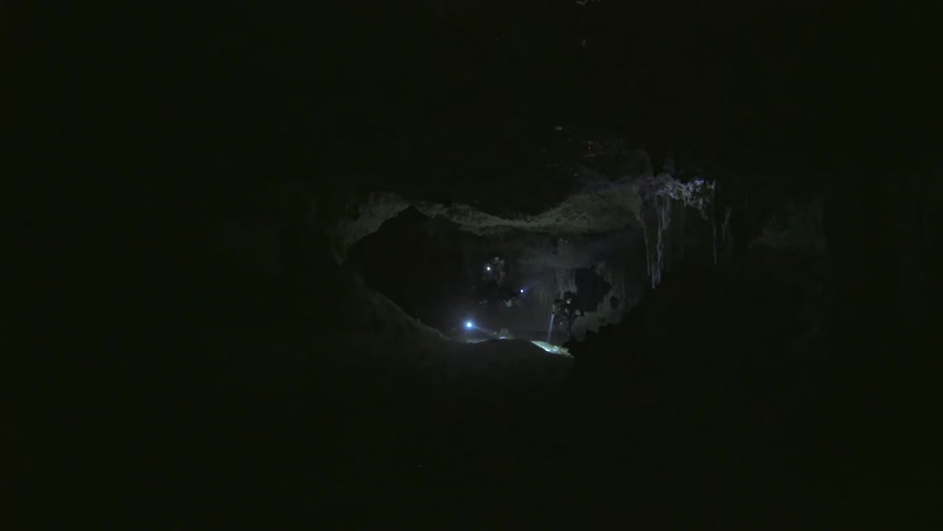 Small group of divers in an underwater cave at night