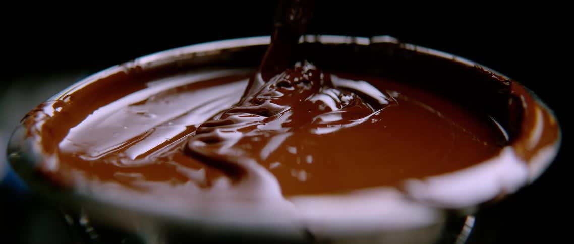 Spoon stirs chocolate sauce in small bowl