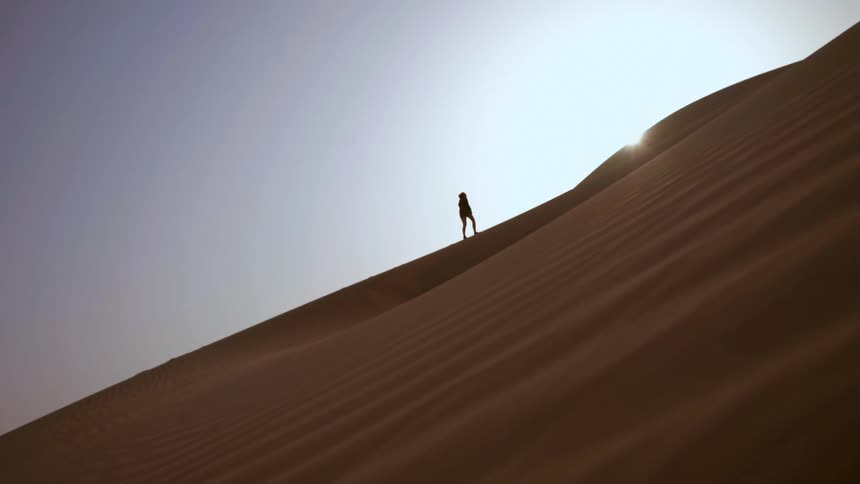 Person climbing a sand dune in the desert