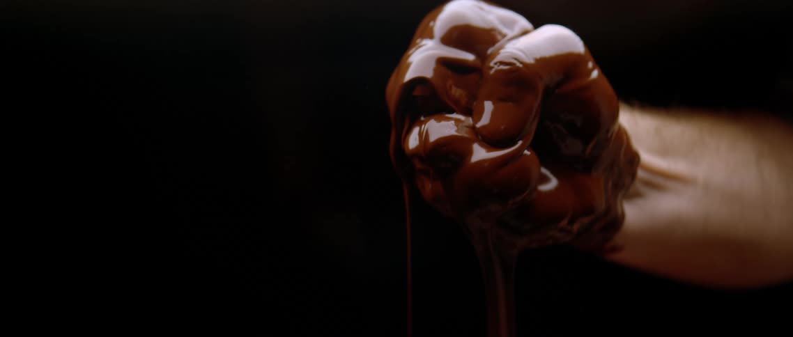 Fist covered in chocolate against a black background