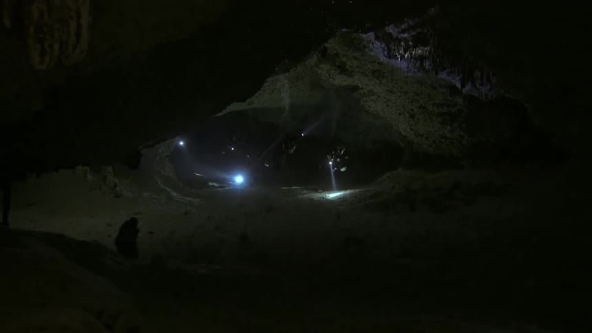 Divers at the bottom of the sea inside a cave with lanterns