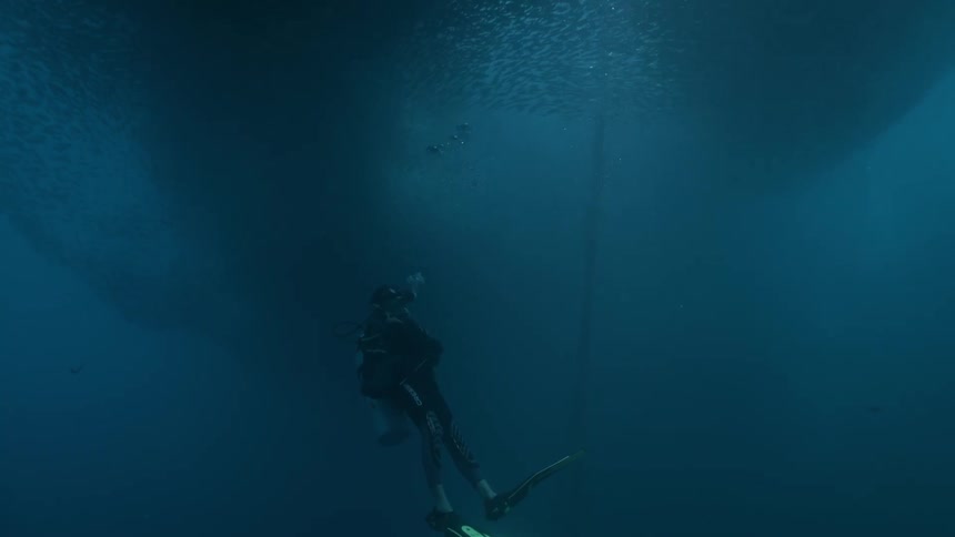A person swimming underwater in a diving suit