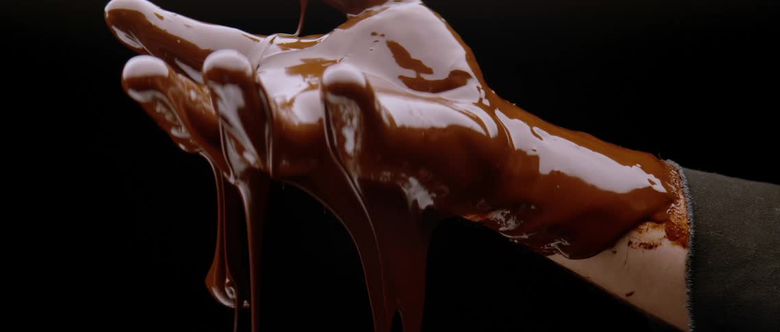 Hands of a person with liquid chocolate dripping