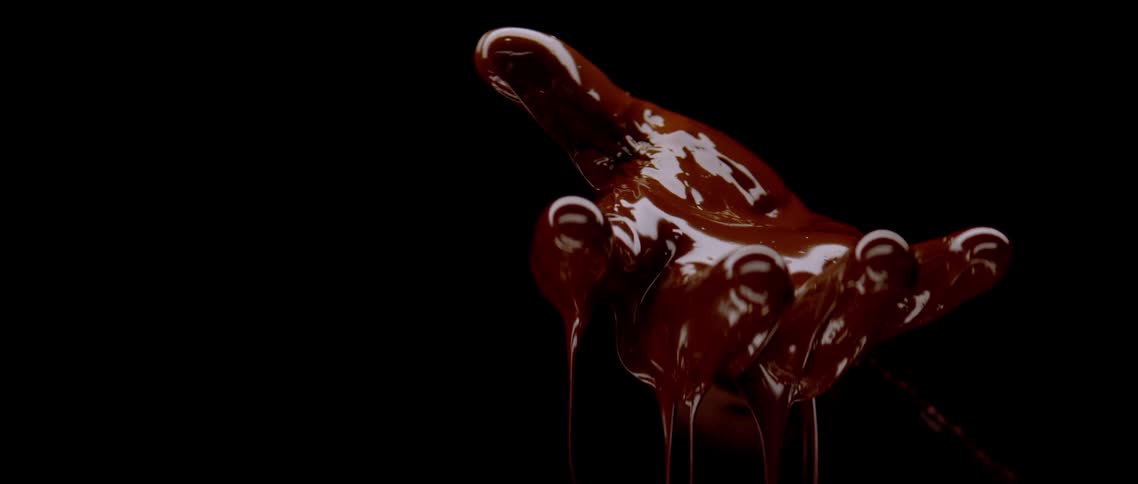An open hand covered in dripping liquid chocolate