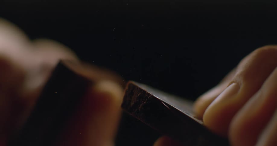 Extreme closeup of hands breaking a slice of chocolate