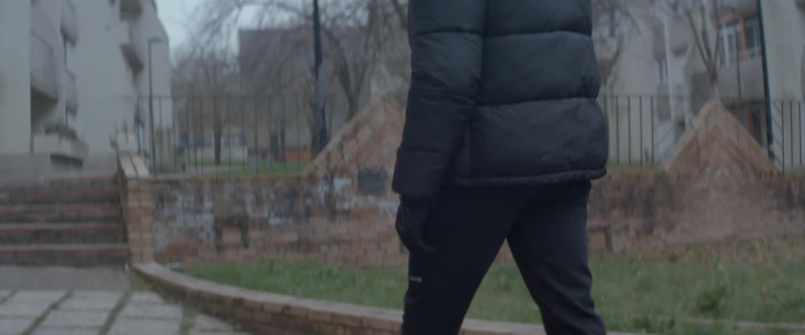 A person wearing warm clothing is walking on a sidewalk