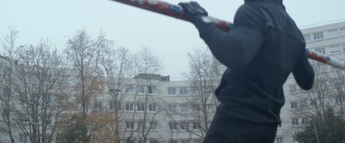 A person wearing a hoodie doing pullups on a pole