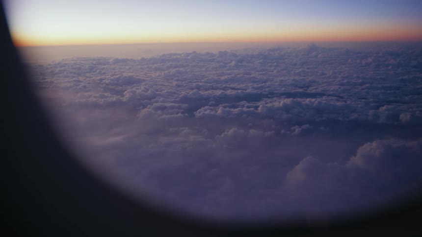 Clouds stretch out to the horizon as seen from a plane window creating a vast and serene sky view
