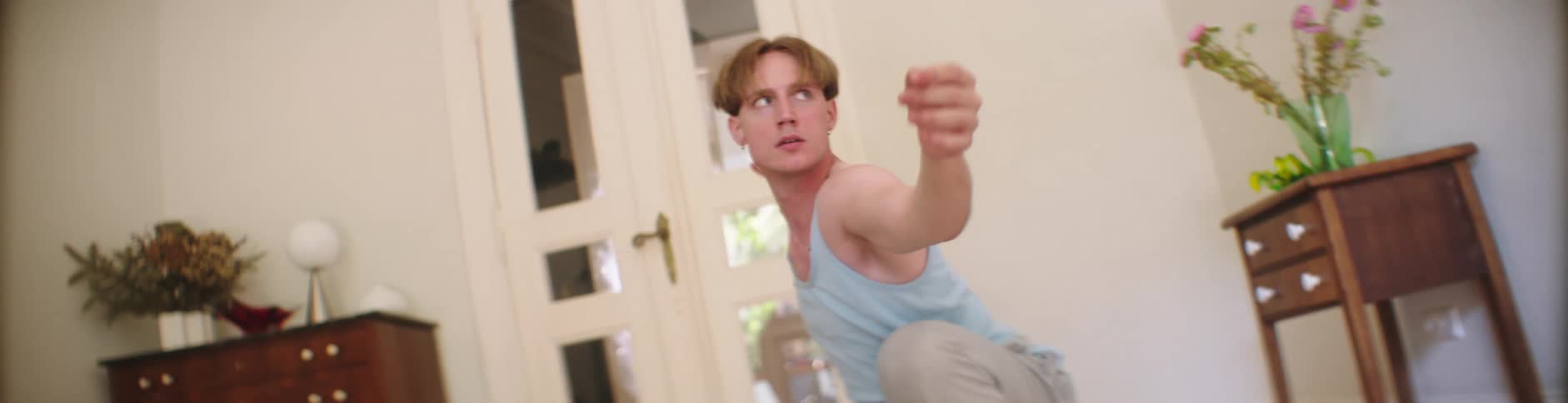 Man stretches both hands while in a squatting position indoor during the day