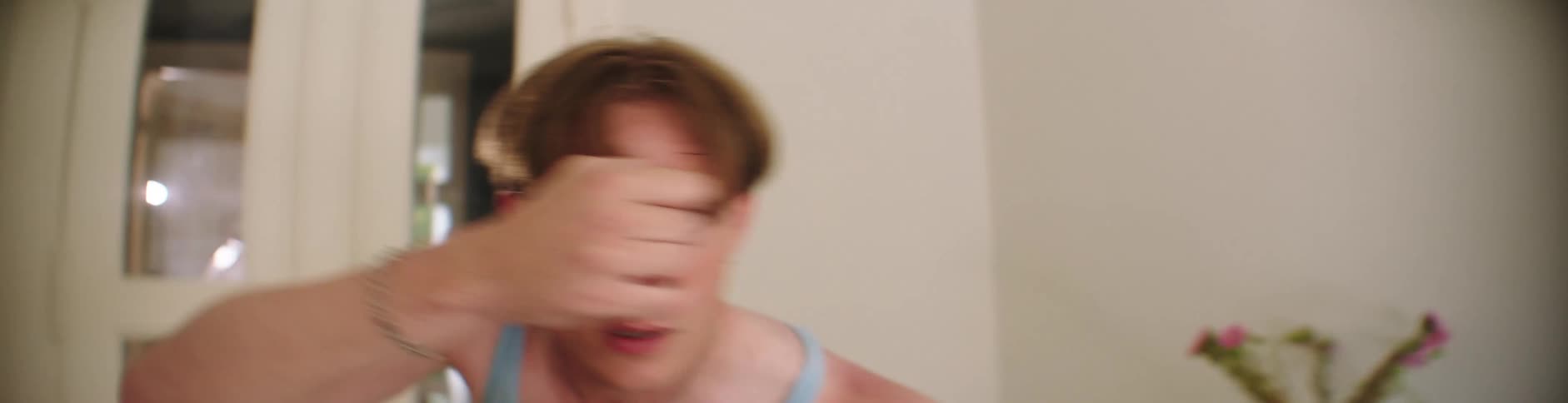 Determined man with light blue tank top dances in room