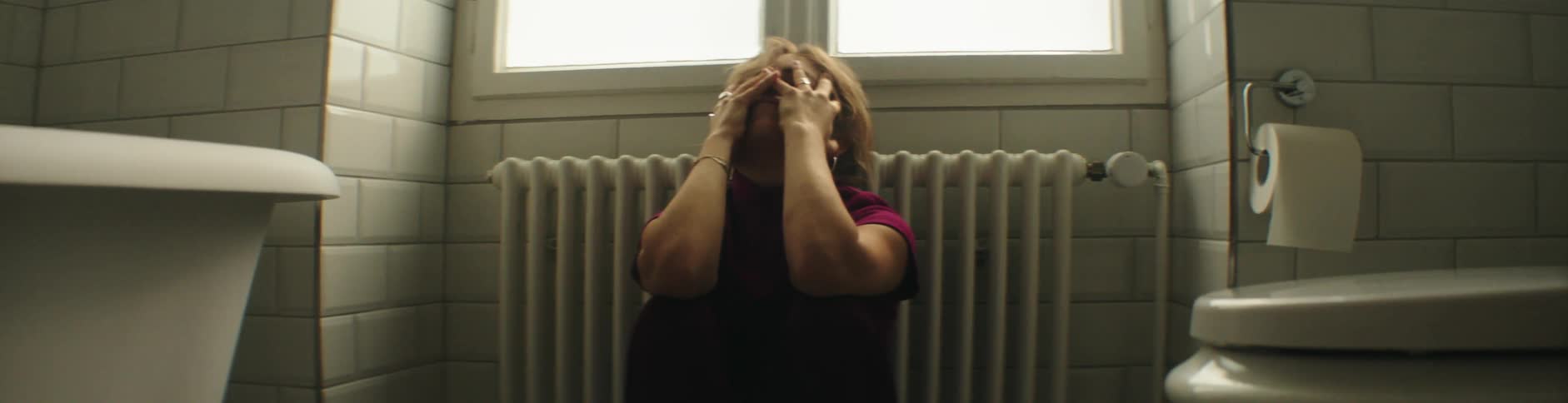 A woman grabs her face in the bathroom