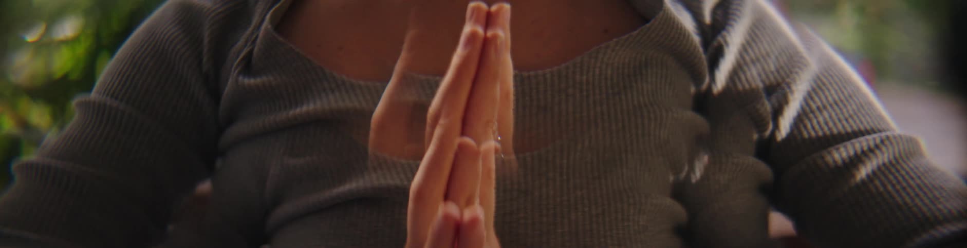 A woman practices yoga with her hands joined together in a meditative pose