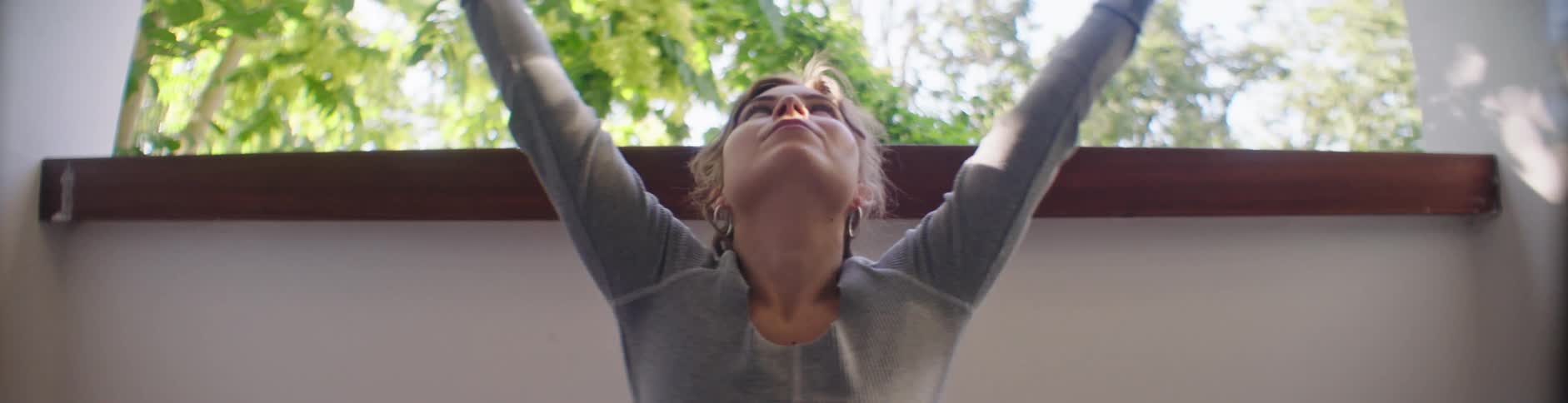 Woman wearing a gray top and yoga pants does yoga on the balcony