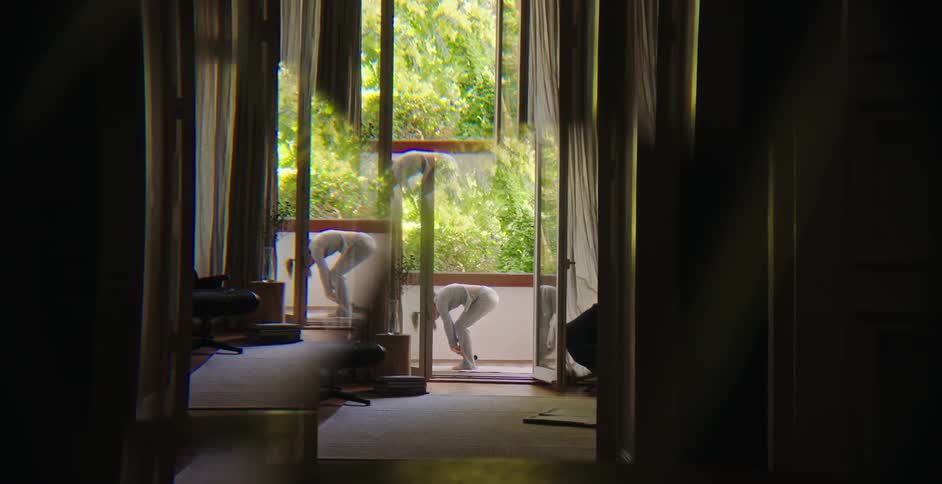 A woman dressed in a gray top and leggings practicing yoga on the balcony