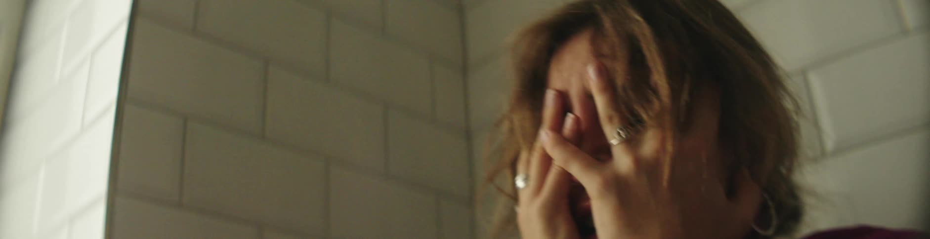 Sad lady inside the restroom with both hands on her face