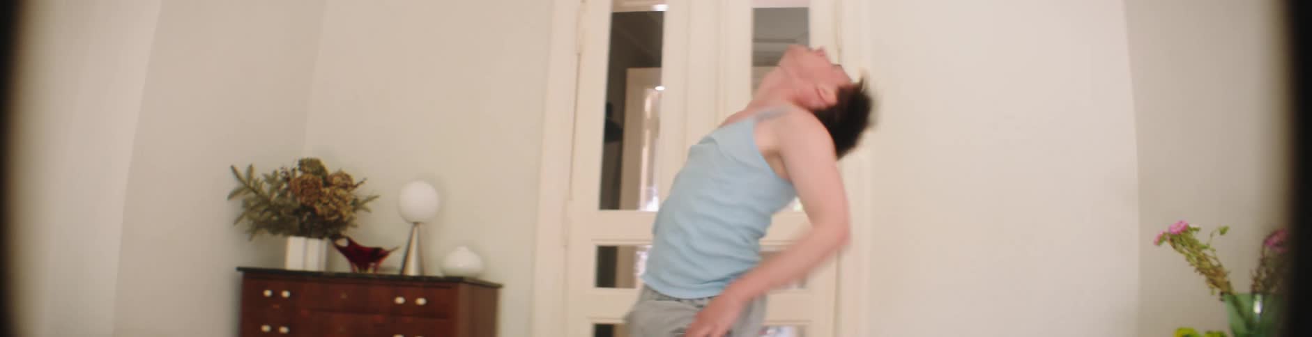 A male dancer flails and contorts his body while dancing indoors