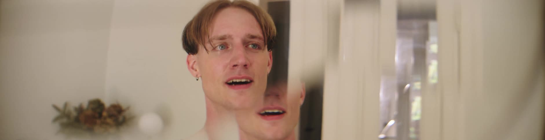 A young man smiles the image of his face is refracted through a prism