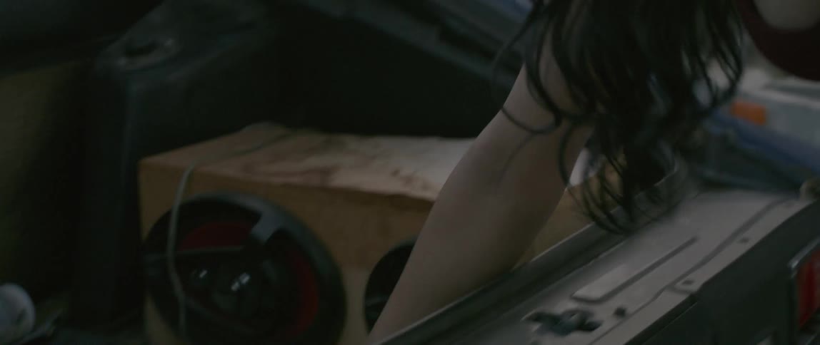 A woman opens the hatch of a vehicle and removes a tool