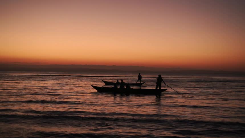 People paddling canoe on the river at sunset