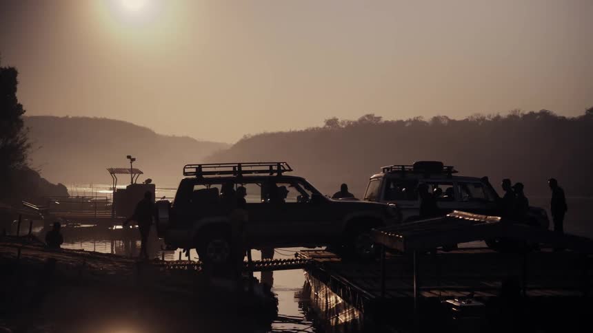 Vehicles drive onto the pier on the river