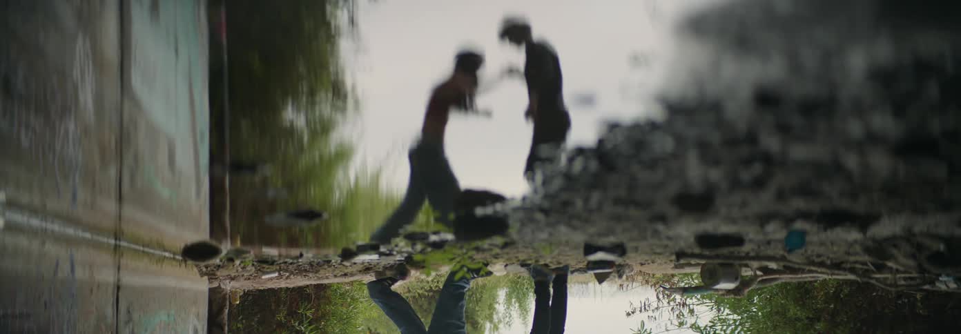 Man assisting his partner in jumping over a puddle in an outdoor setting