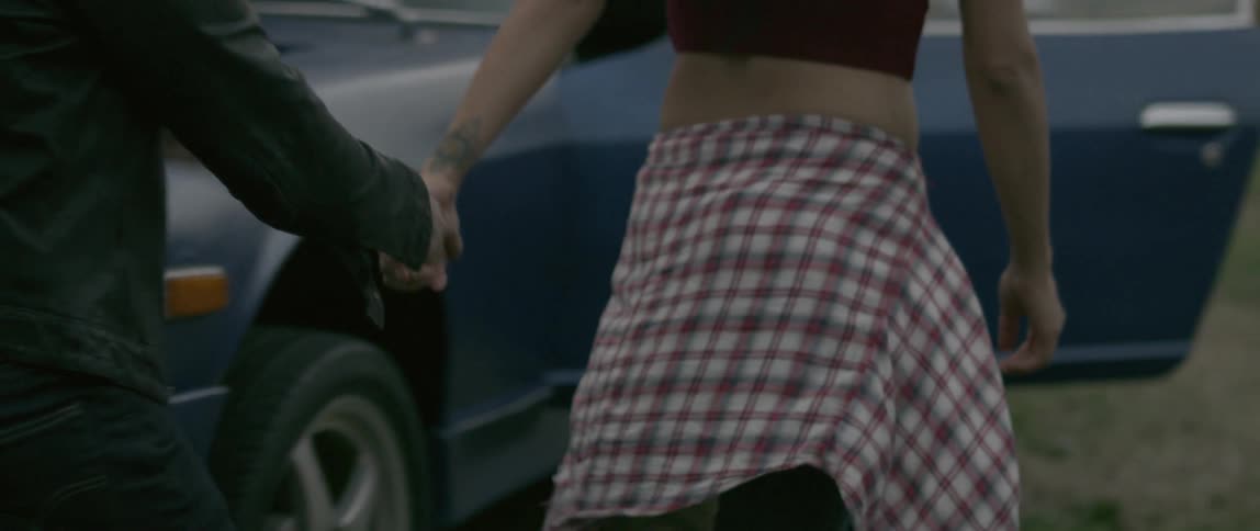 A man and woman hold hands walking next to a vehicle