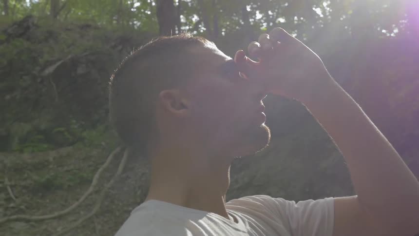 Man shields his eyes from the sun in the forest