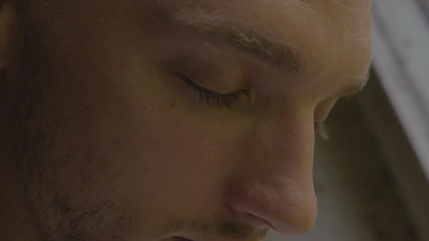 A man is looking down then closes his eyes briefly