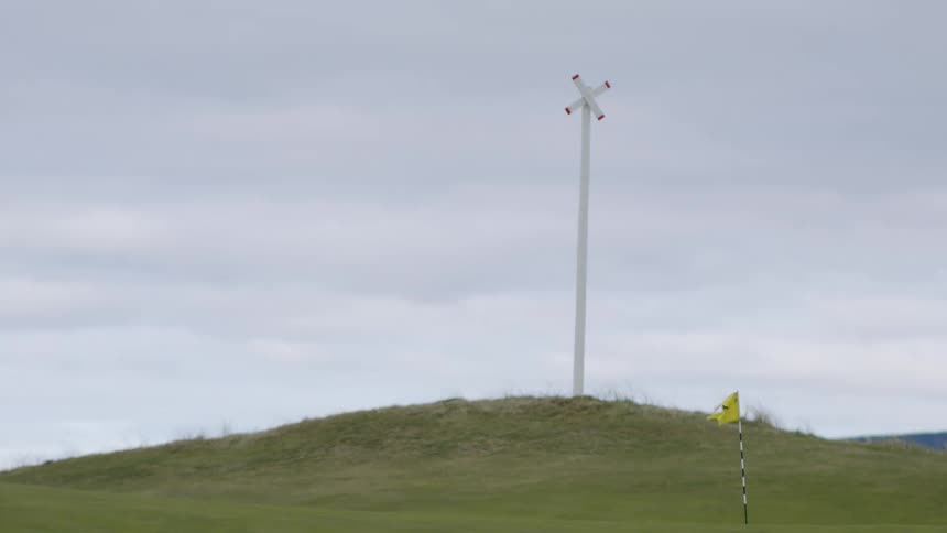 A person in a golf field moving by with the flag pole in the golf cup