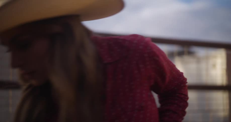 A blonde woman in a cowboy hat is plowing the land