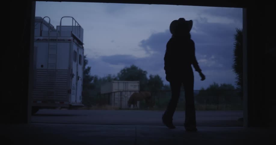 A silhouette of a person wearing a hat opening a garage door