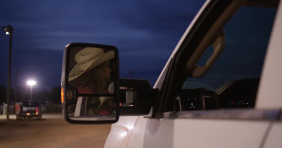 Lady on cowboy hat driving a car at night