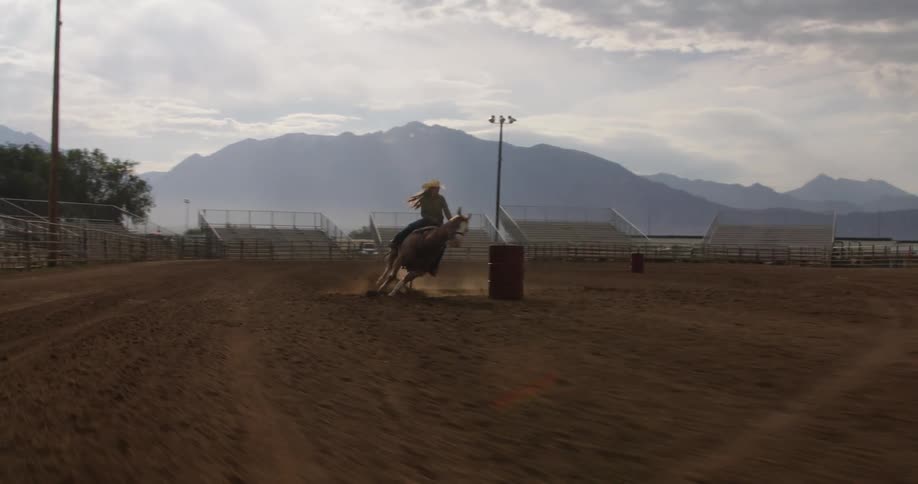 A person riding a horse that is running on a ranch and passing through obstacles