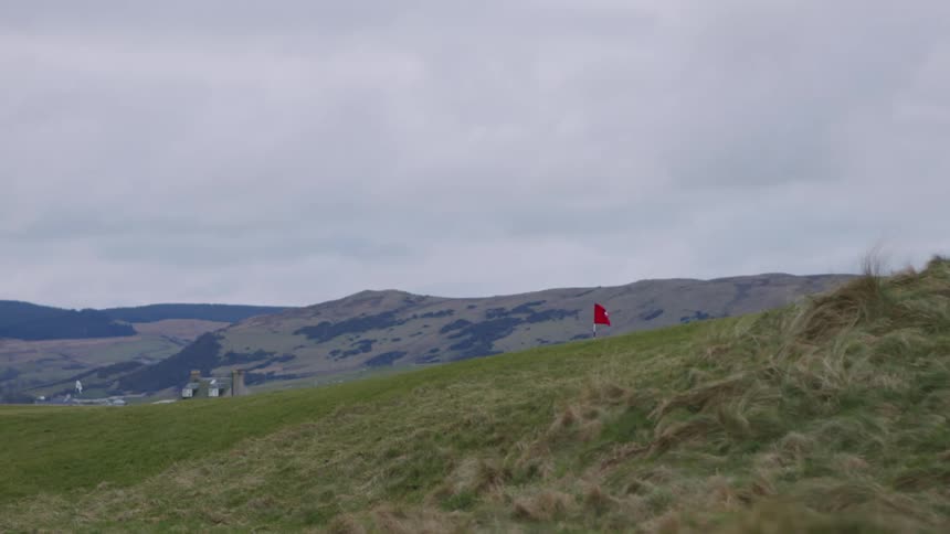 A red flag waving in the wind in a meadow