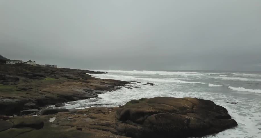 Large rocks line the shore with waves hitting them