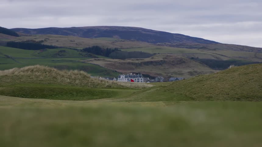 View of a golf course with a house on the horizon