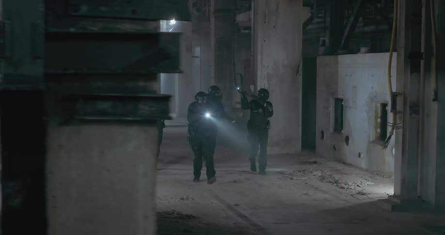A tactical team with black equipment and clothing and weapons with flashlights