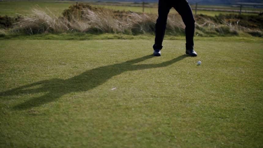A person swinging at a golf in a golf course